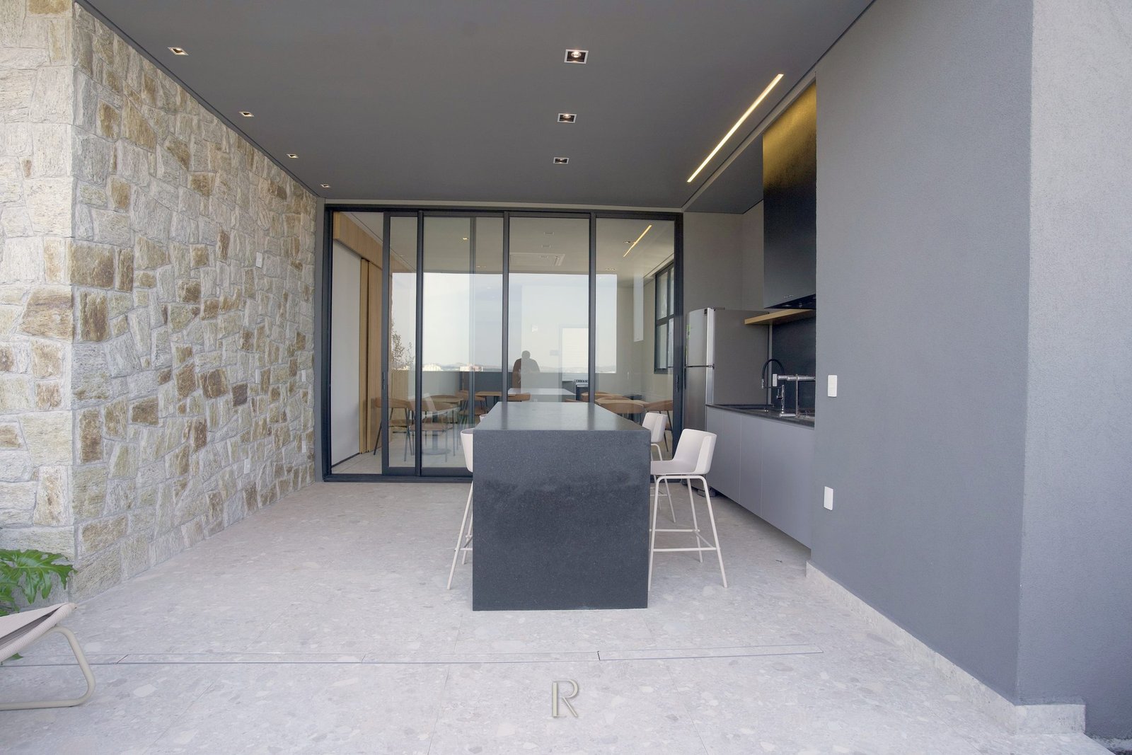 Espaço gourmet do Matiss, com ilha, parede de pedra e caixa envidraçada